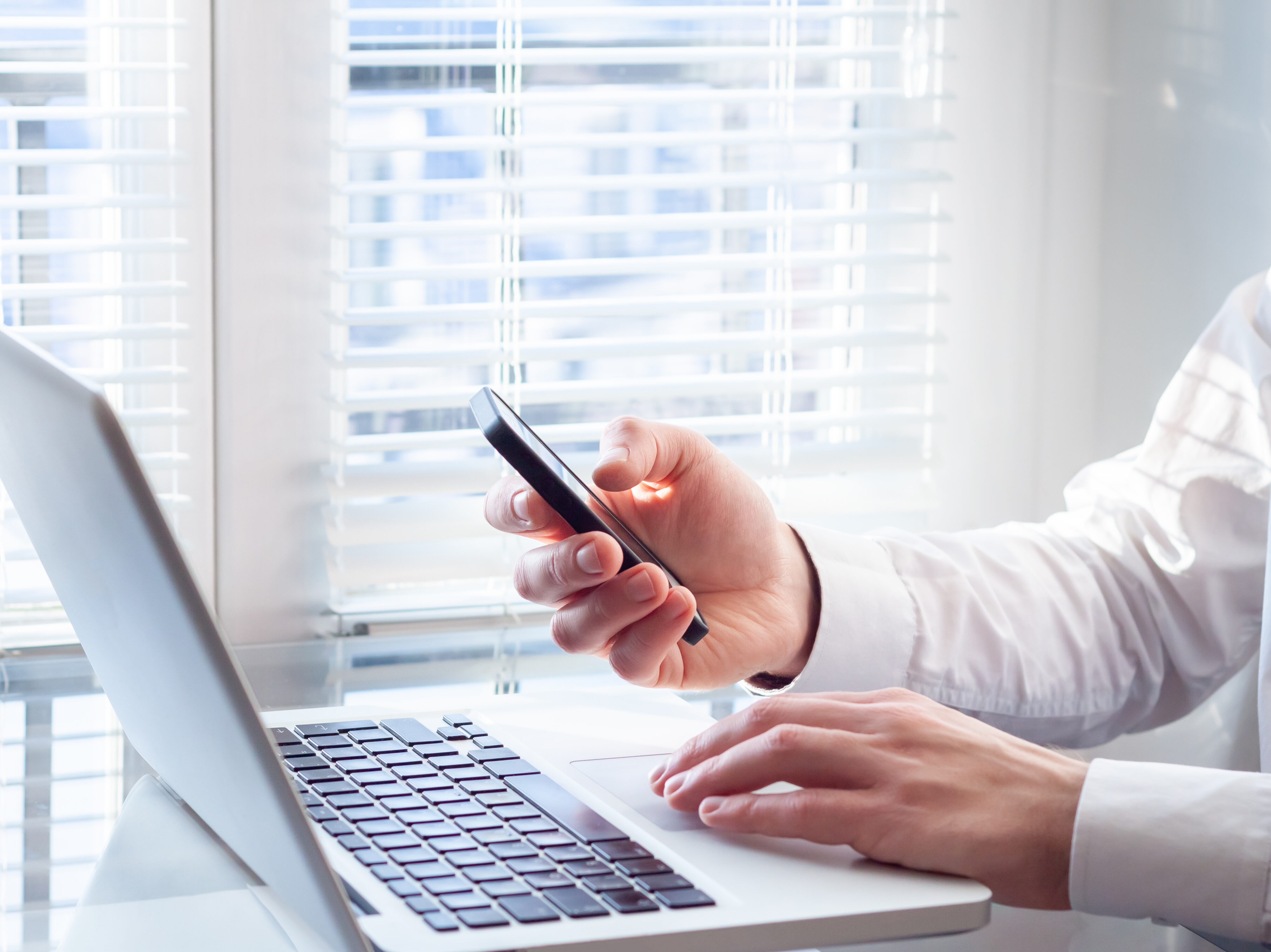 Businessman working with laptop and smartphone, bright office, f